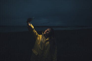 Frankreich, Bretagne, Landeda, Dünen von Sainte-Marguerite, Frau macht ein Selfie am Strand bei Nacht - GUSF00594