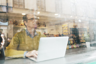 Man using a laptop behind Window - FOLF06249