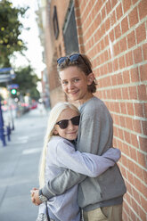 Bruder und Schwester umarmen sich auf dem Bürgersteig - FOLF06356