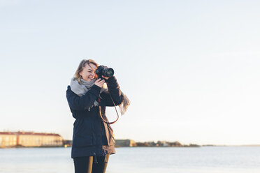 Woman taking photograph by sea - FOLF06367