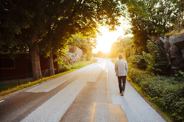 Mann geht bei Sonnenuntergang auf der Straße - FOLF06372