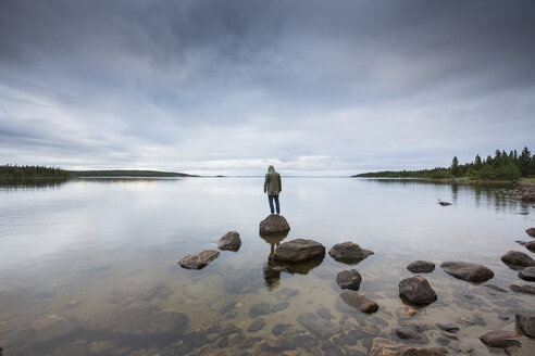 Mann steht auf einem Felsen an einem See - FOLF06379