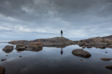 Woman standing on rock by a lake - FOLF06383