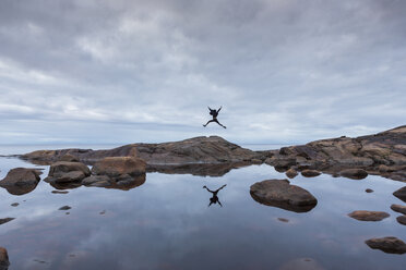 Frau springt auf Felsen am See - FOLF06384