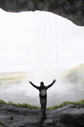 Woman standing with arms raised in front of Waterfall - FOLF06426