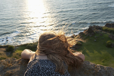 Young girl lying on her stomach looking out to sea - FOLF06497