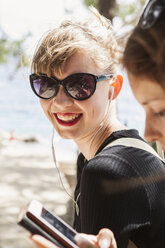 Junge Frau am Strand, die Musik hört - FOLF06529