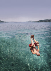 Young man somersaulting into the sea - FOLF06537