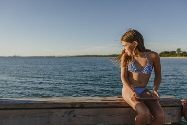 Junges Mädchen sitzt auf einer Bank am Meer - FOLF06575