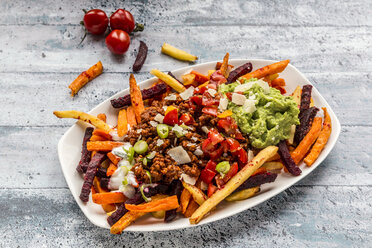 Gemüsepommes mit vegetarischer Bolognese, Guacamole, Joghurt-Dip, Tomaten, Frühlingszwiebeln und Parmesan auf dem Teller - SARF03639