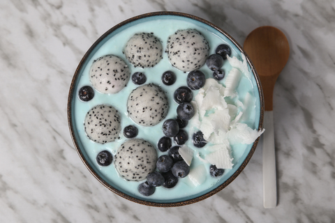 Blaue Smoothie-Bowl mit Kokosraspeln, Blaubeeren und Drachenfruchtkugeln, lizenzfreies Stockfoto