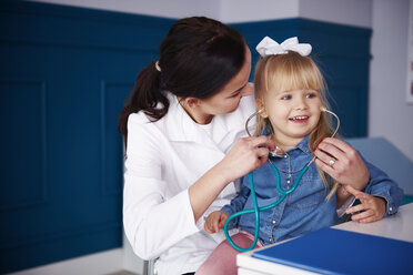 Doctor and girl playing with stethoscope in medical practice - ABIF00213