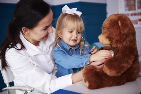 Doctor and girl examining teddy in medical practice stock photo