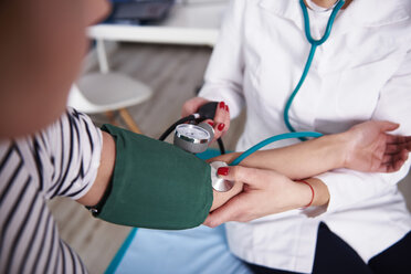 Arzt misst Blutdruck einer Frau in einer Arztpraxis - ABIF00223