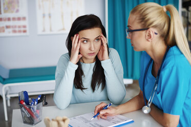Besorgte Frau im Gespräch mit einem Arzt in einer Arztpraxis - ABIF00232