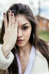 Portrait of a beautiful brunette woman covering an eye - MGOF03736