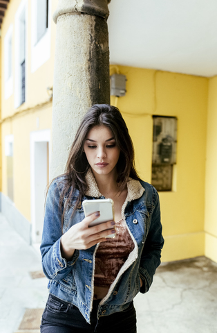 Young woman in a town checking her smartphone stock photo