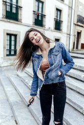 Portrait of a laughing brunette woman in a town - MGOF03754