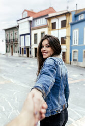 Portrait of a smiling brunette woman holding hand in a town - MGOF03756