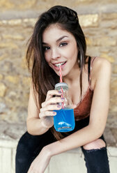 Portrait of a smiling brunette woman drinking blue lemonade - MGOF03761