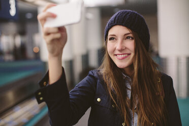 Glückliche Frau, die ein Selfie macht, während sie am Flughafen steht - CAVF32128
