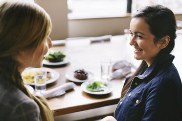 Hohe Winkel Ansicht der glücklichen weiblichen Freunde sprechen, während am Tisch im Restaurant sitzen - CAVF32133