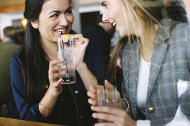 Glückliche Freunde unterhalten sich bei einem Drink im Restaurant - CAVF32134