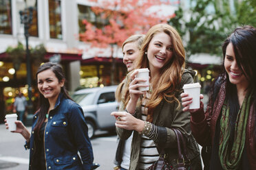 Fröhliche Freundinnen trinken Kaffee beim Spaziergang auf der Straße - CAVF32143