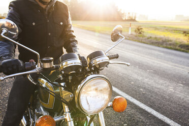 Mittelteil eines Motorradfahrers, der an einem sonnigen Tag auf dem Motorrad sitzt - CAVF32160
