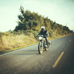 Männlicher Motorradfahrer auf einer Landstraße gegen den Himmel - CAVF32162