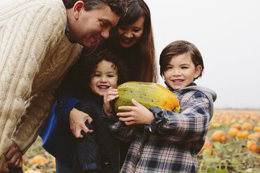 Glückliche Eltern betrachten ihre Söhne mit Kürbis auf dem Bauernhof - CAVF32176
