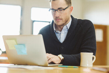 Businessman using laptop computer at desk in office - CAVF32186