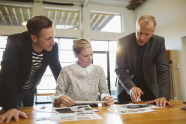 Business people discussing paperwork at table in office - CAVF32218