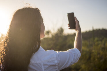 Rückansicht einer Frau, die ein Selfie gegen den klaren Himmel macht - CAVF32348