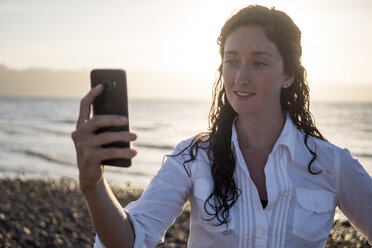 Frau, die ein Selfie macht, während sie am Ufer steht - CAVF32349
