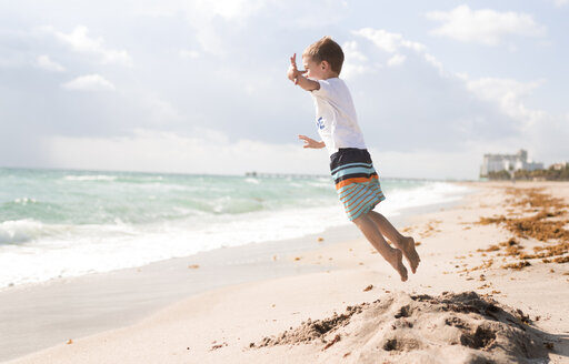 Seitenansicht eines am Strand springenden Jungen vor bewölktem Himmel - CAVF32374