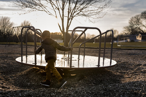 Junge, der auf dem Spielplatz Karussell fährt - CAVF32379