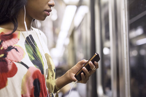 Frau hört Musik auf dem Handy während der Fahrt im Zug - CAVF32419