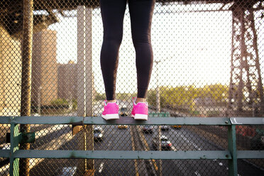 Niedriger Ausschnitt einer Joggerin, die auf dem Geländer einer Fußgängerbrücke steht - CAVF32447