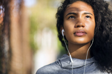 Nahaufnahme einer Joggerin, die Musik hört und nach oben schaut - CAVF32466