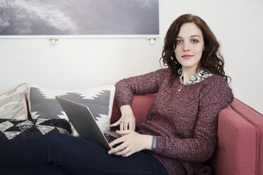 Porträt einer Geschäftsfrau, die einen Laptop benutzt und auf dem Sofa sitzt - CAVF32505