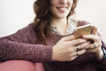 Businesswoman using smart phone while sitting on sofa - CAVF32507