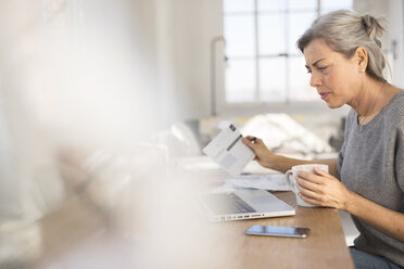 Konzentrierte Frau bei der Arbeit am Tisch im Heimbüro - CAVF32612