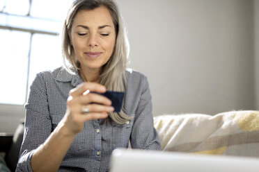 Frau schaut beim Online-Shopping auf ihre Debitkarte - CAVF32639