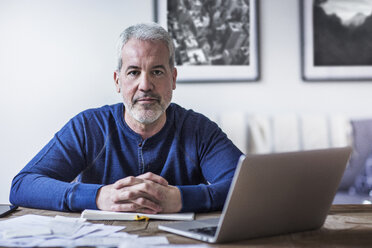 Portrait of confident mature man sitting at table in home - CAVF32656