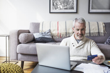 Älterer Mann benutzt Kreditkarte und Laptop beim Online-Shopping zu Hause - CAVF32657
