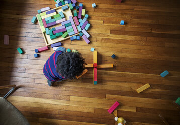 Overhead view of boy playing with toy blocks on hardwood floor at home - CAVF32672
