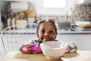 Porträt eines niedlichen Mädchens, das sich auf einen Tisch mit einer Frühstücksschüssel im Vordergrund stützt - CAVF32674