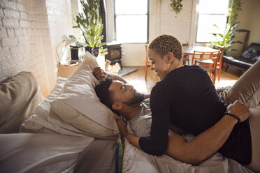 Glückliches romantisches Paar, das sich gegenseitig ansieht, während es zu Hause auf dem Bett liegt - CAVF32703
