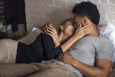 Romantic young couple lying on bed at home - CAVF32712